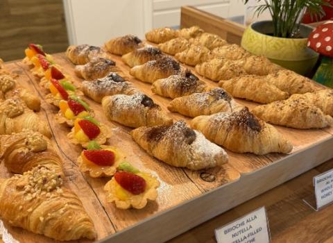 Vassoio di brioche e pasticcini con frutta fresca su un tavolo di legno.