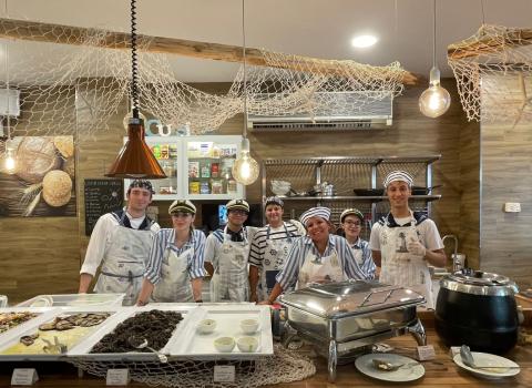 Staff in abiti marinari dietro un buffet di pesce in un ristorante.