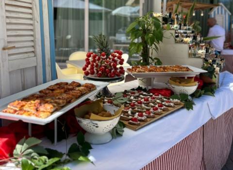 Buffet all'aperto con stuzzichini e decorazioni, sotto ombrelloni bianchi.