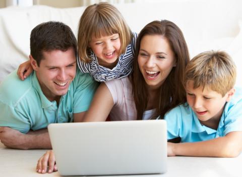 Famiglia felice guarda qualcosa di divertente su un laptop insieme.