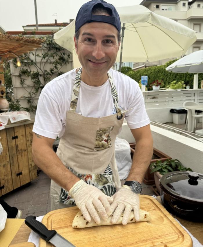 Uomo prepara un wrap in un ambiente all'aperto con guanti e grembiule.